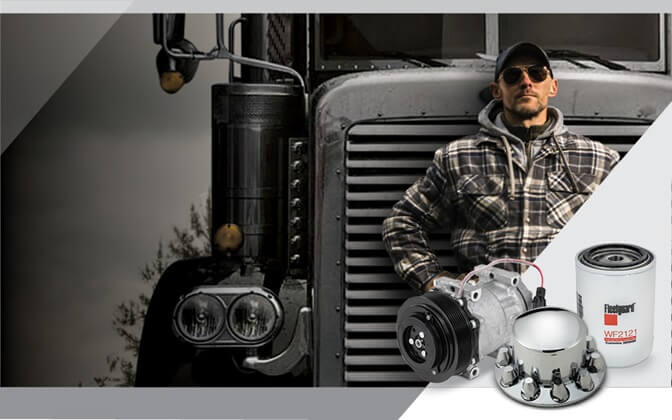 Truck driver in front of truck and pile of assorted truck parts