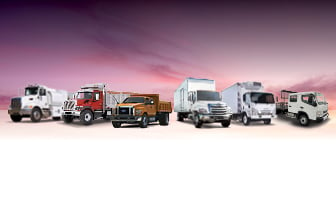 Line up of commercial semi trucks on pink background