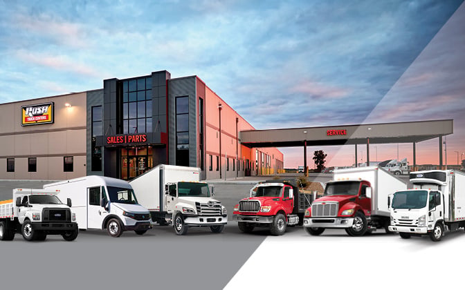 Line up of commercial trucks in front of Rush Truck Centers dealership