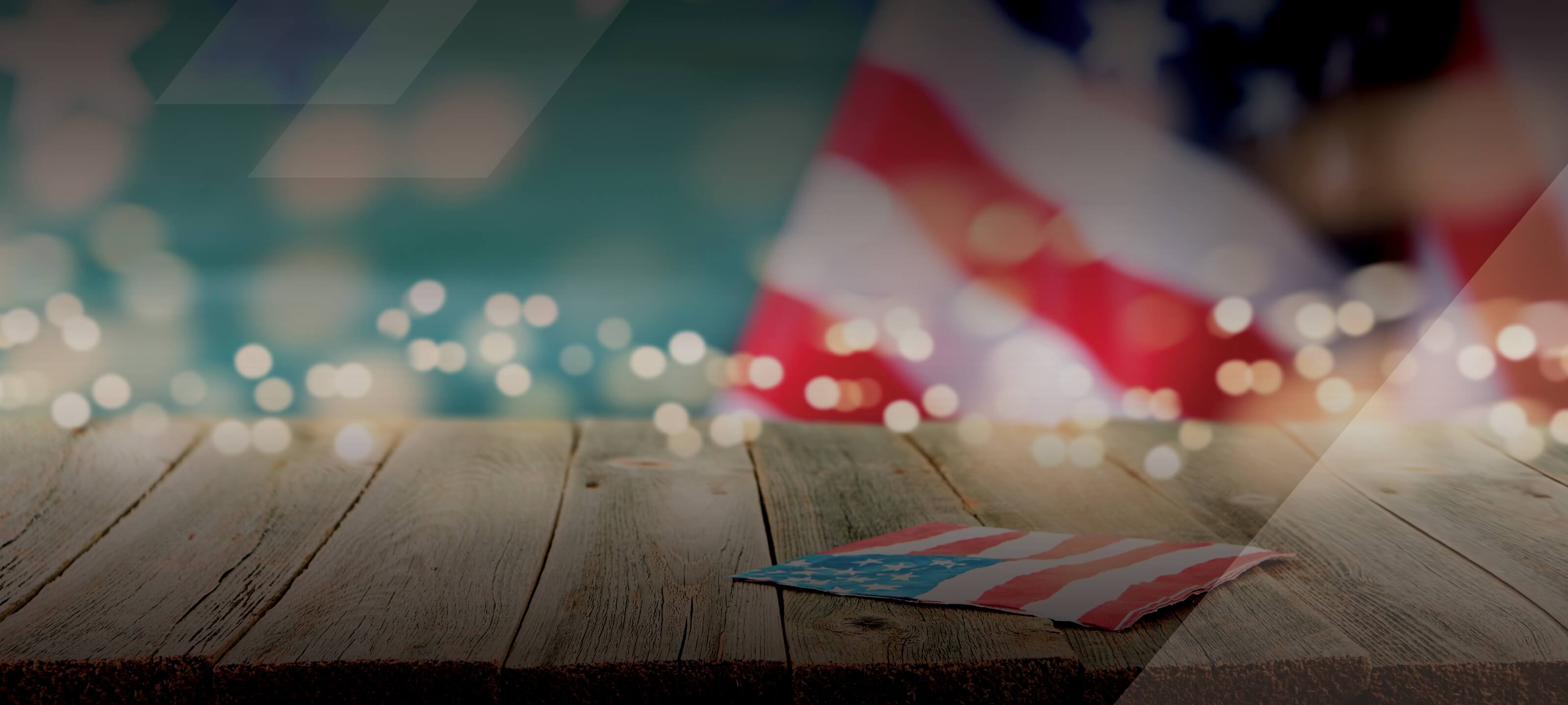 American flag napkin laying on wood table with twinkle lights in the background