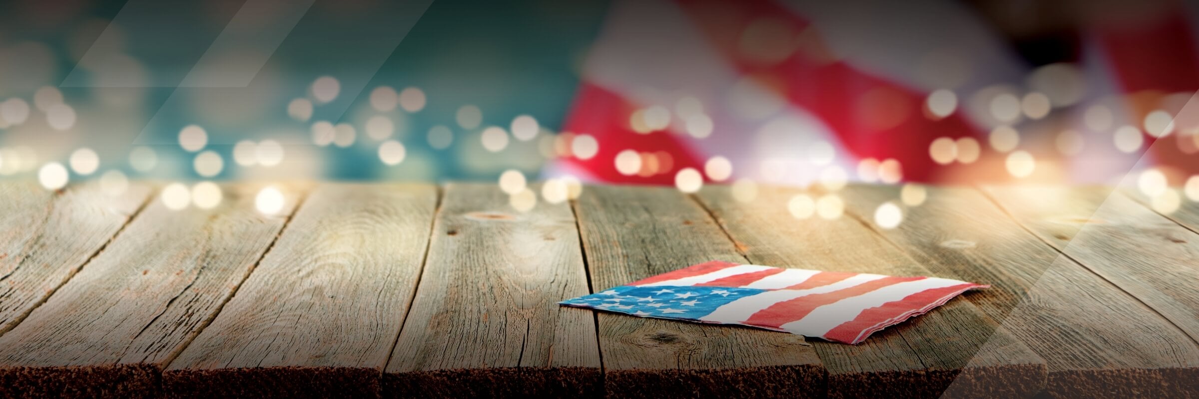 American flag napkin laying on wood table with twinkle lights in the background