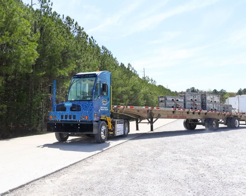 ACTT terminal tractor transporting flatbed with materials on it