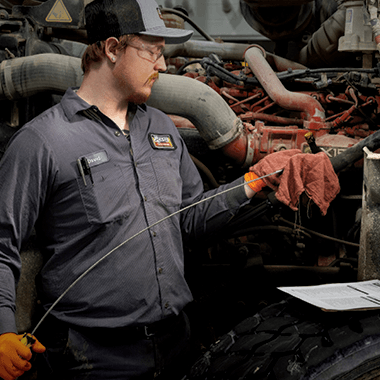 Technician checking truck fluid levels during inspection