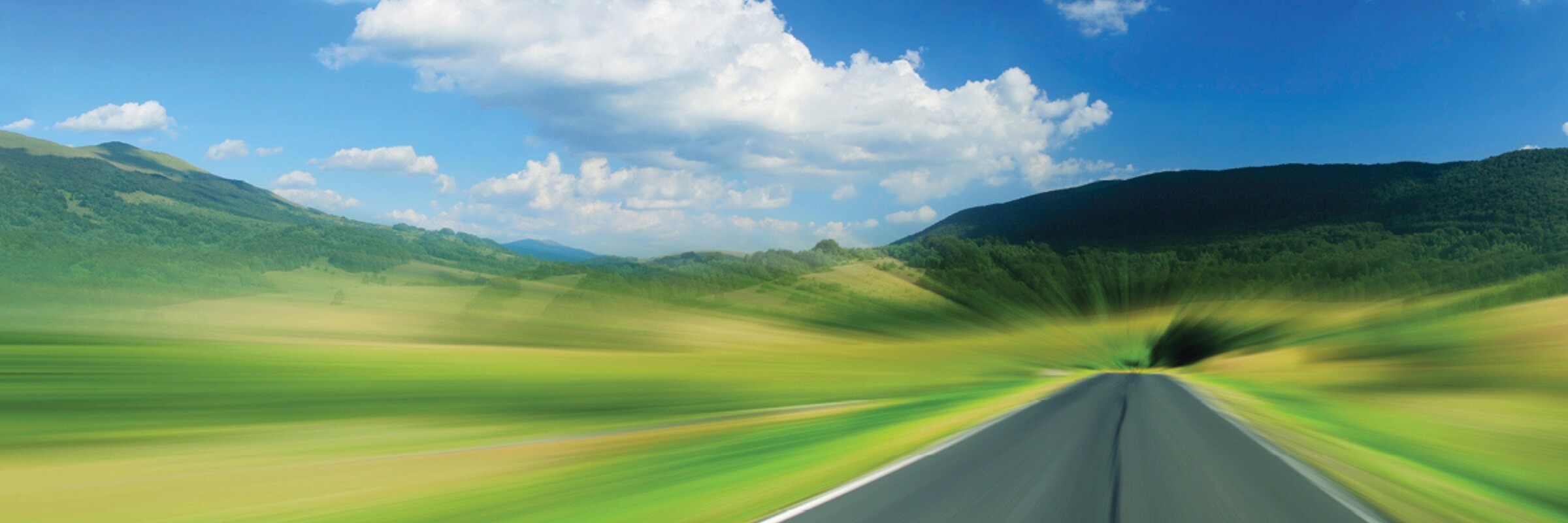 open road surrounded by green fields
